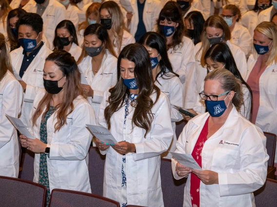 Doctor of Nursing Practice students recite the student oath of responsibility after they were each presented with their white coats. 