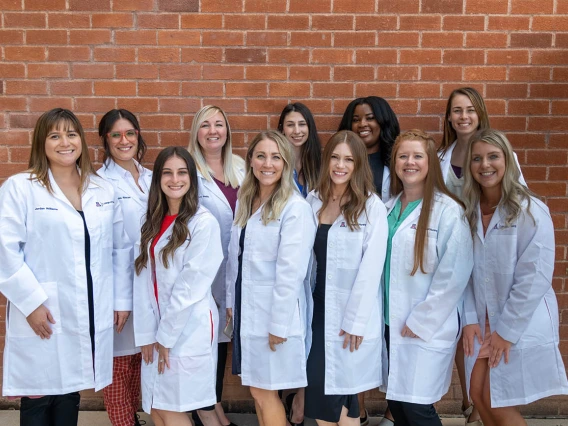 A group of Doctor of Nursing Practice students who received their white coats during the ceremony pause for a photo outside of Crowder Hall. 