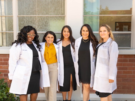 Doctor of Nursing Practice students (from left) Emily Ngunjiri, Paula Maria Hernandez, Tiana Sanchez, Alexandra Robles and Kimberly Heath show off their new white coats after the ceremony. 