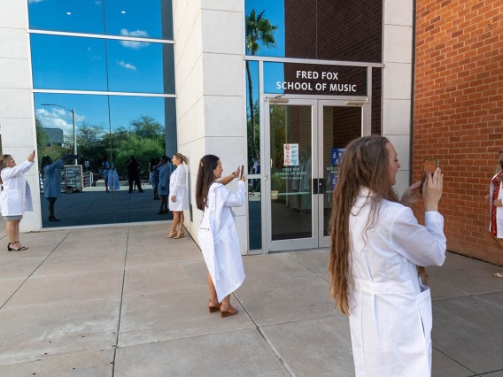 Newly white-coated Doctor of Nursing Practice students take photos of each other after their ceremony ended. 