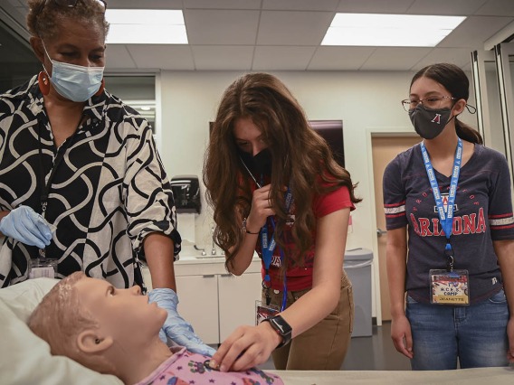 ASTEC’s Rochelle Marshall, left, helps ACES camper Ayleen Cruz find the patient simulator’s heart beat as Jeanette Mendoza watches.