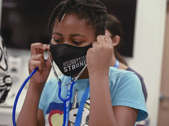 ACES camper Victoria Vigbedorh puts on a stethoscope so she can listen to the patient simulator’s heartbeat.