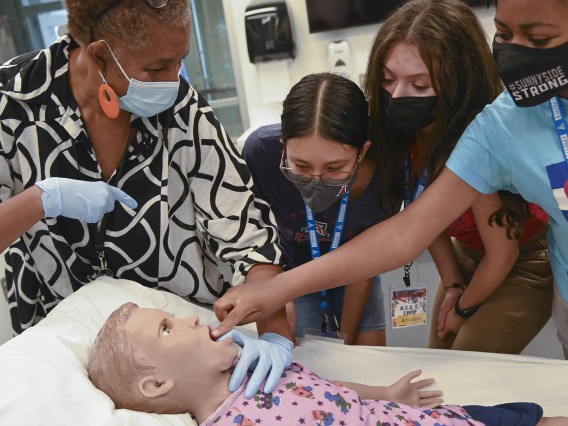 Southern Arizona Research, Science and Engineering Foundation (SARSEF) campers practice a procedure on Hal, the pediatric patient simulator, as explained to them by ASTEC’s Rochelle Marshall. The girls, all part of the Applied Career Exploration in Science (ACES) camp were, from left, Jeanette Mendoza, Ayleen Cruz and Victoria Vigbedorh.