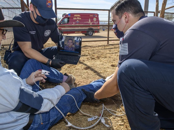 Tucson emergency department physician Dr. Joshua Gaither consults with Weber and Saez about treatment options using the AzREADI telehealth technology. (Note: This was a simulated accident scene for demonstration purposes.)