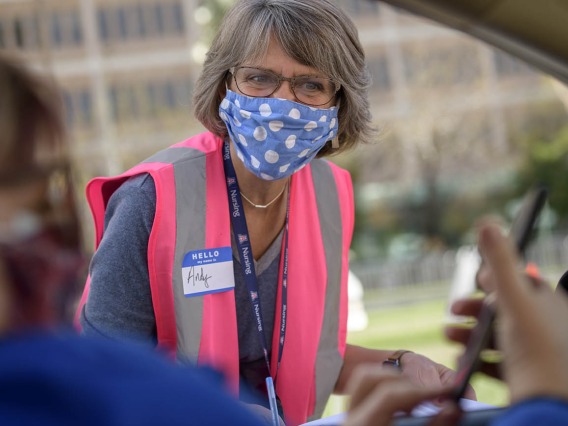 Andrea Fisher, College of Nursing associate vice president for development, confirms vaccination appointments before drivers pull up to the vaccine distribution site.