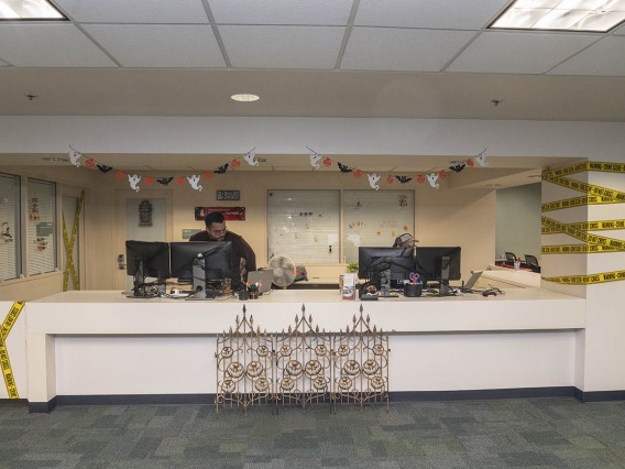 A wide reception desk with Halloween decorations all around it, including yellow caution tape, little ghosts hanging from the ceiling. 
