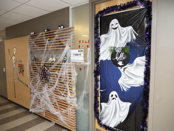 Hallway with spider webs and other Halloween decorations on the walls and ghosts on a door. 