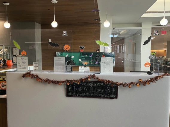 The reception desk in the Health Sciences Library is covered with various Halloween decorations. 