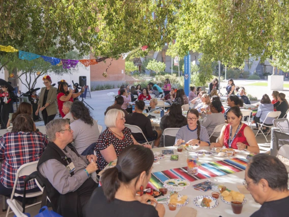 Dozens of people sitting at tables in a courtyard eating and drinking. 