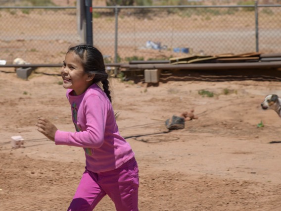 smiling Navajo girl running in a yard