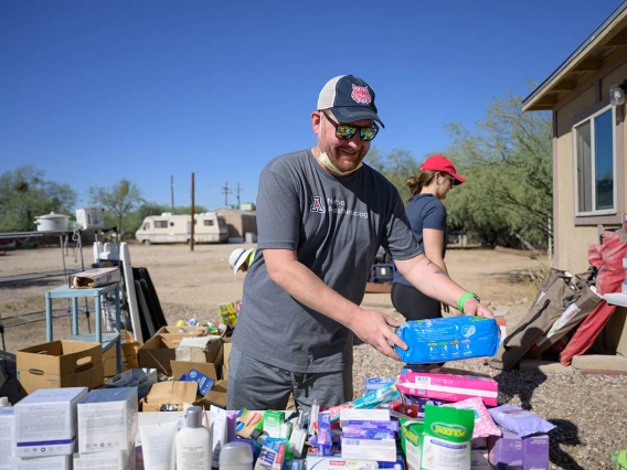 A man in a baseball hat stands outside a building as he sorts donated toiletrees.