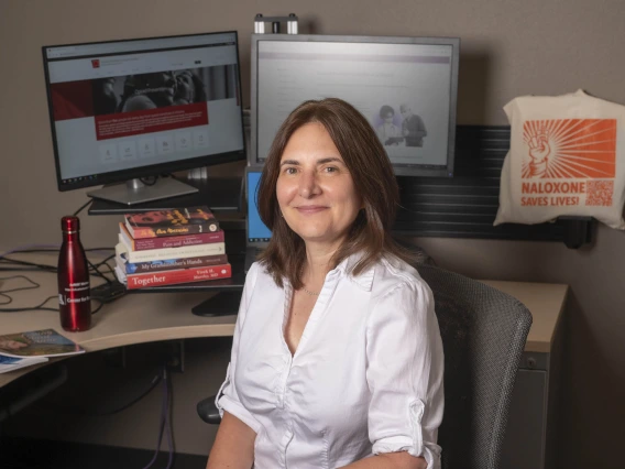 Bridget Murphy at her desk with computer monitors and books.