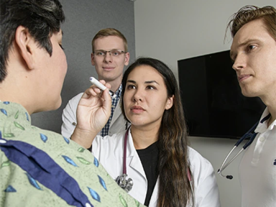 Students examine a simulated patient