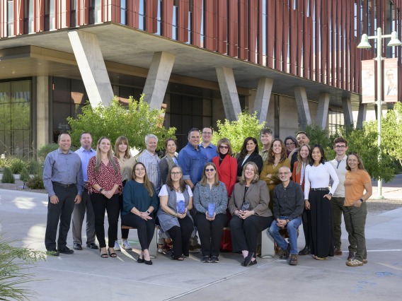 About 20 members of the UArizona Health Sciences Office of Communications stand for a group photo outside of the Health Sciences Innovation Building.