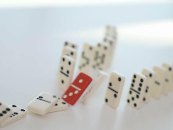 A line of white dominoes with a red domino in the middle representing a gene mutation