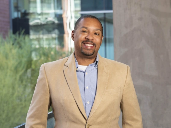 Photo of Michael D.L. Johnson in a blue shirt with a tan sports coat. 