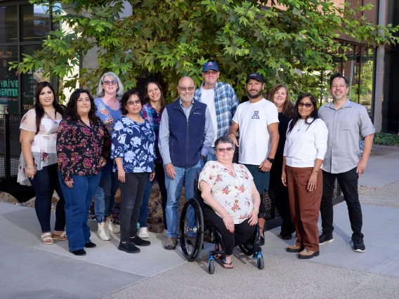 A group of 12 men and women pose for a photo in an outdoor setting. 