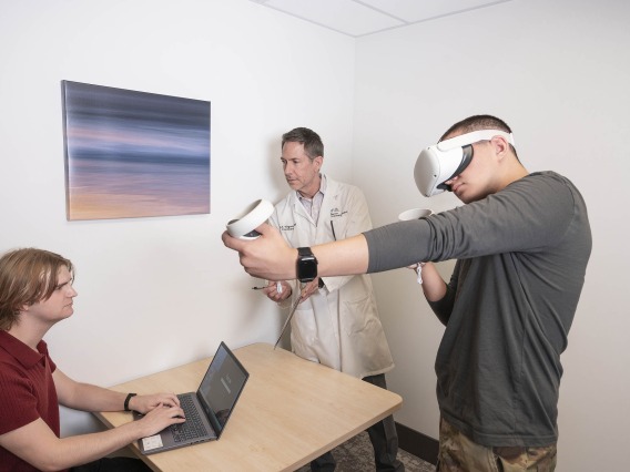 person using virtual reality headset and controllers while University of Arizona Health Sciences researchers observe in the background