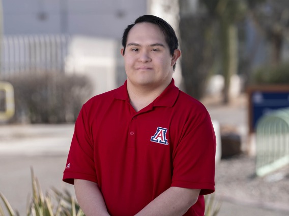 Portrait of Gabe Martinez wearing a University of Arizona logoed, red collared shirt.