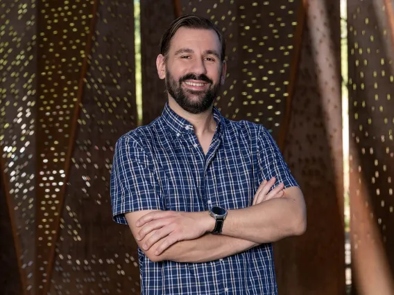 Portrait of young man with beard smiling with arms crossed in short sleeved button-up shirt