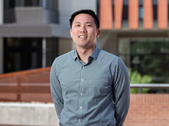 Portrait of a young Asian man wearing a button-up shirt standing outside.