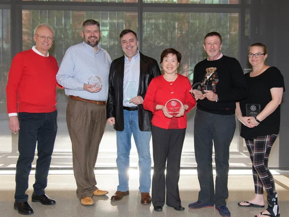 Five people standing in a line facing viewer holding Pharmacy Faculty/Staff recognition awards.