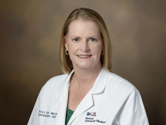 Blonde woman wearing a white medical coat sits for a portrait.