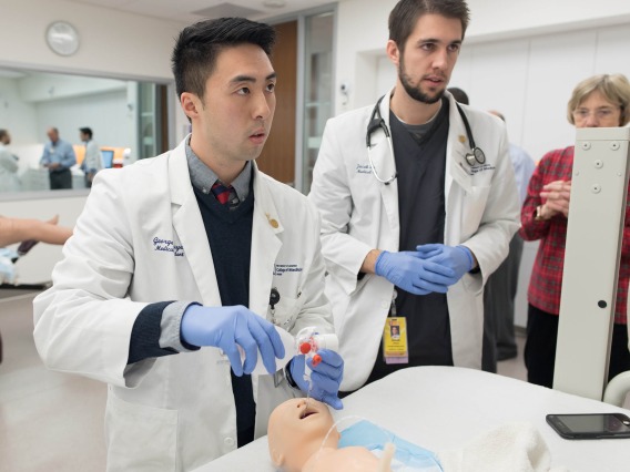 Two medical students training on a mannikin in a medical simulation center