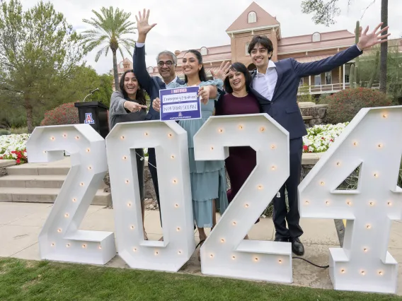 a medical student and her family celebrate behind a large 2024 sign 