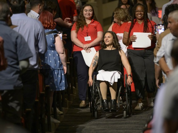 A pharmacy student in a wheelchair leads the class procession into Centennial Hall for their white coat ceremony.