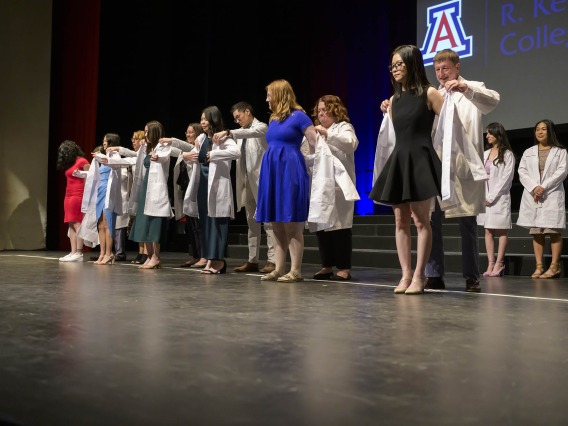 Several University of Arizona pharmacy students are presented their white coats by faculty members. 