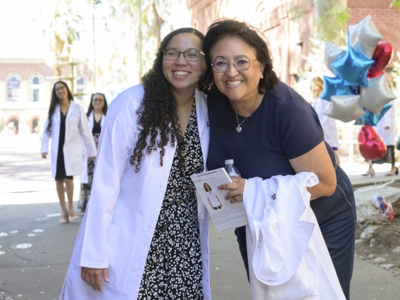 A pharmacy student smiles while standing with a professor outside after leaving the University of Arizona R. Ken Coit College of Pharmacy white coat ceremony. 