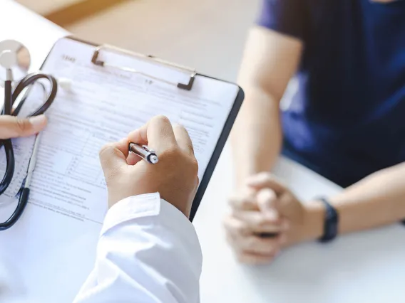  Doctor giving prescription to a patient and filling out medical form on a clipboard