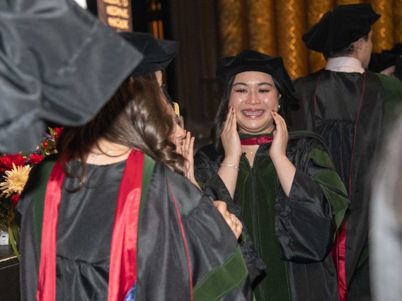 A University of Arizona College of Medicine – Phoenix student in graduation regalia holds her hands to her face as she smiles at the conclusion of the commencement ceremony.
