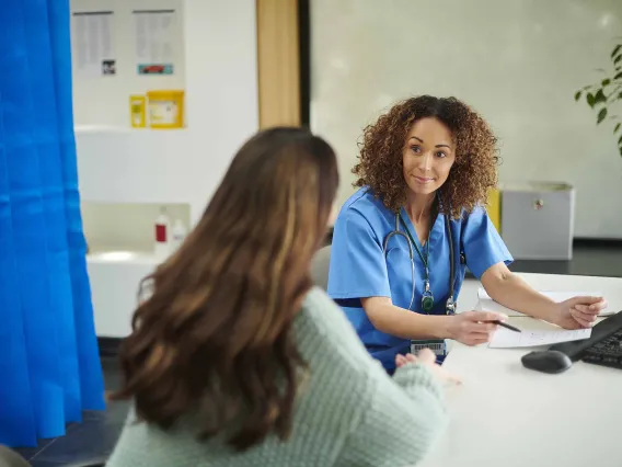 primary care physician smiles at patient while reviewing prescription details