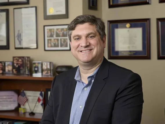 Portrait of Michael Grandner in front of a wall lined with framed photos and certificates.