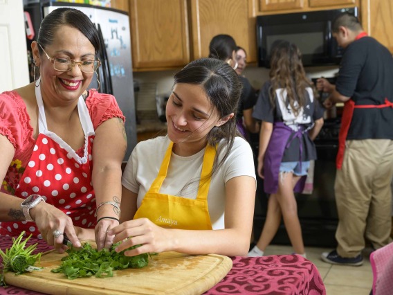 A Hispanic family in a kitchen preparing a healthy meal together 