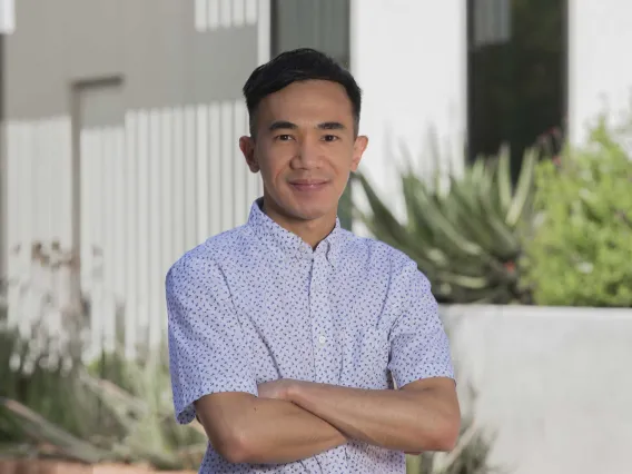 Portrait of a young professor with arms crossed and smiling while standing outside. 