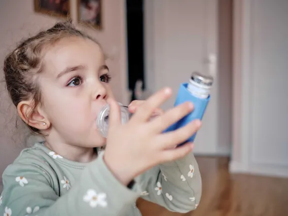 Young child using inhaler with a spacer device.