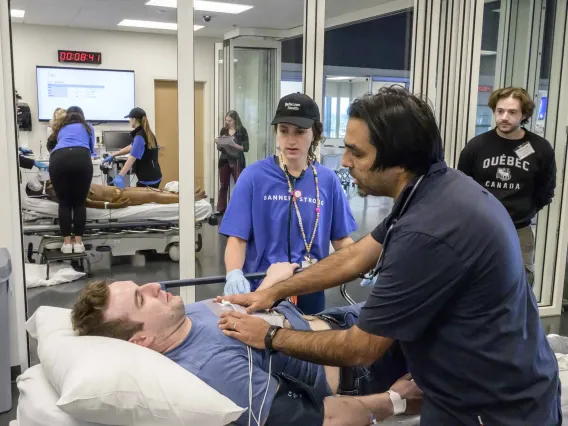 Several emergency room residents work on a volunteer patient in an ER-like setting as part of a medical simulation competition.