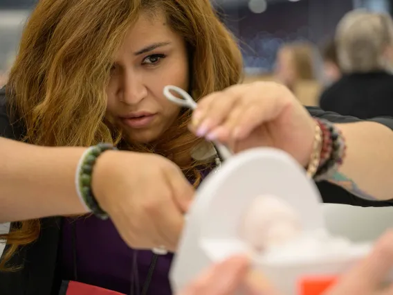 A nursing student focuses intently as she practices a medical procedure on a piece of simulation equipment. 