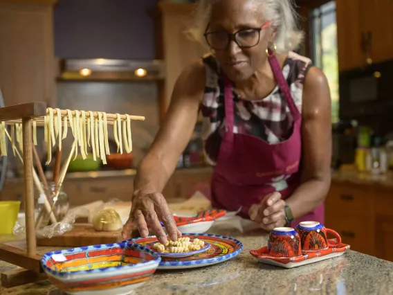 Dr. Juanita Merchant wears an apron as she makes a fresh pasta meal in her kitchen. 