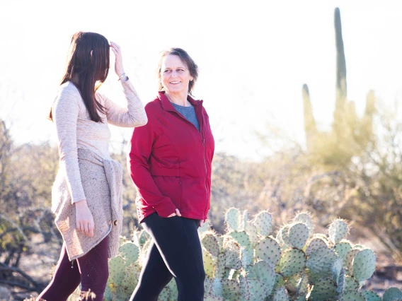 Lorre Laws, PhD, walks in the desert next to a young woman.