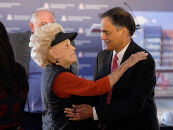 A woman puts her hand on the shoulder of a man in a suit as they talk. 