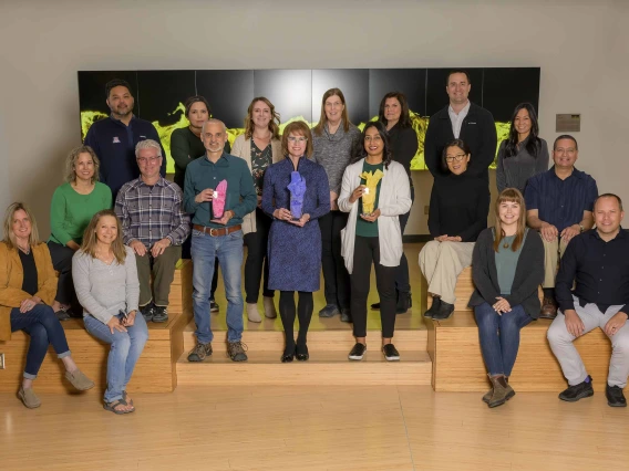 The University of Arizona Health Sciences Office of Communications staff stand together holding three PRSA awards.