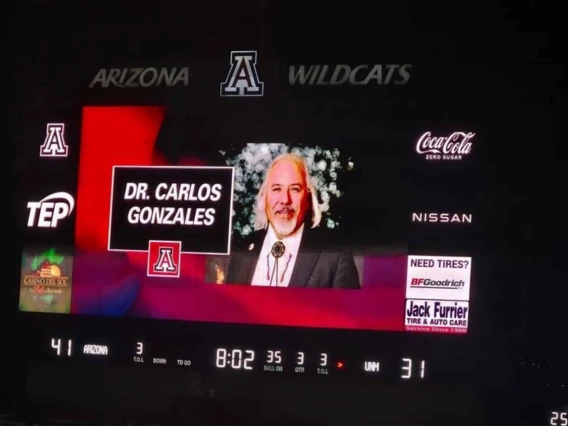 Photo of a large video screen showing a picture of Carlos Gonzales, MD, at a recent University of Arizona football game.