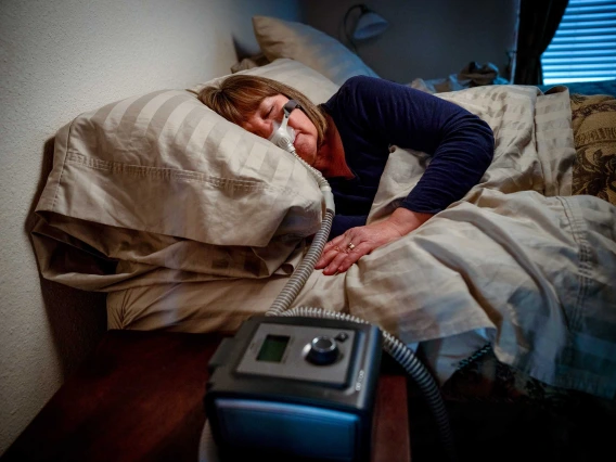 A woman in a bed using a CPAP machine