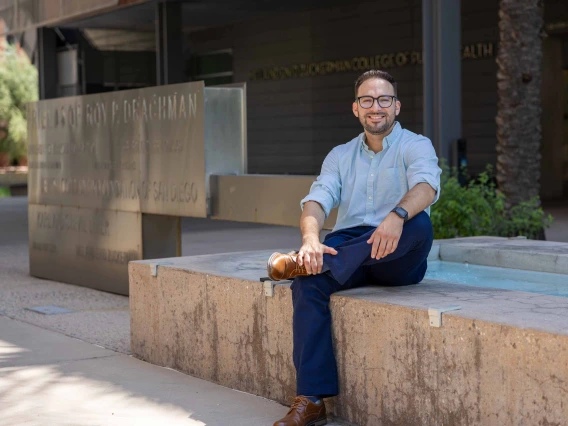 Rogelio Robles-Morales sitting next to a water fountain in front of the University of Arizona Mel and Enid Zuckerman College of Public Health