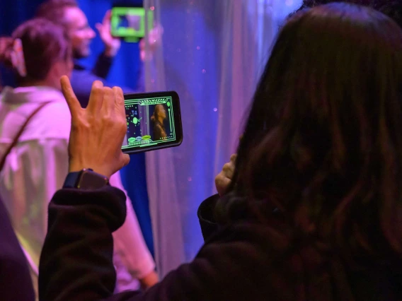 Three people, two holding up cell phones and watching the screens, at the Hearing the Invisible event at the Universit of Arizona