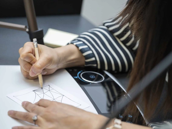 Close-up photo of a hand gripping a pencil, doodling on paper.